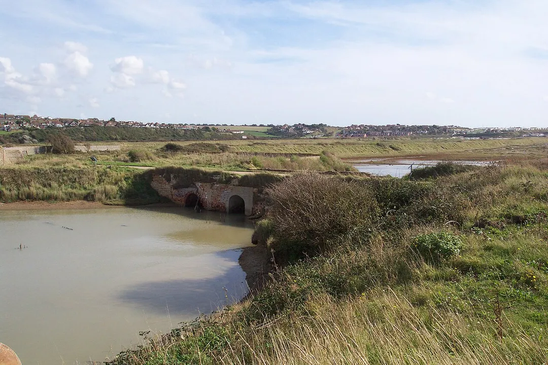 Taken by Tim Trent 
Showing the ruins of the en:Tide Mills tidal mill en:sluice from the seaward (riverward) side on a rising tide.  Shown are two arches.  The right hand one connects to the visible opening in en:Image:Remains of Tide Mills mill race sluice - millpond side.jpg