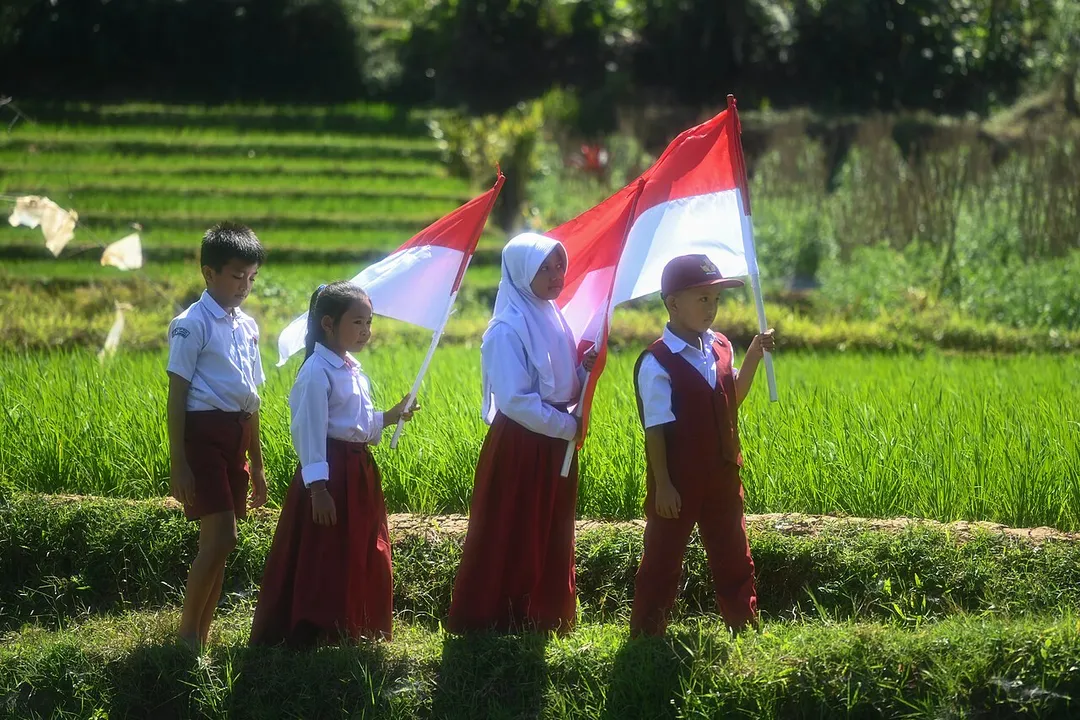 Indonesian elementary school children go to their school through the ricefields for flag ceremony in the morning