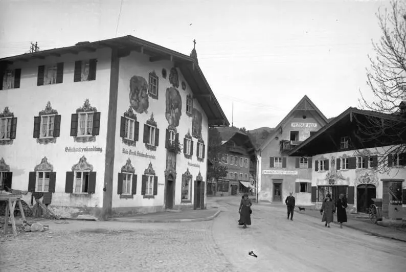 For documentary purposes the German Federal Archive often retained the original image captions, which may be erroneous, biased, obsolete or politically extreme. Oberammergau rüstet zu seinen grossen Festspiel-Wochen! Die weltberühmten Passionsspiele in Oberammergau nehmen am 11. Mai ihren Anfang, zu welchen Zehntausende aus aller Welt erwartet werden. Blick in eine Strasse in Oberammergau mit den hübschen mit Gottesbildern bemalten Häusern.