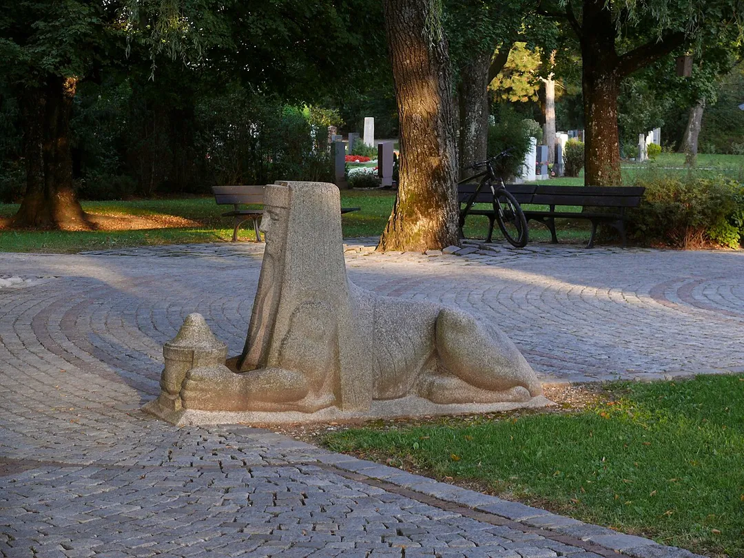 Oberhaching, Friedhof: Vor der neuen Aussegnungshalle stehen zwei ägyptisierende Sphingen, die anscheinend von einem Vorgängerbauwerk (oder von einem sehr monumentalen Grabmal) übernommen wurden.