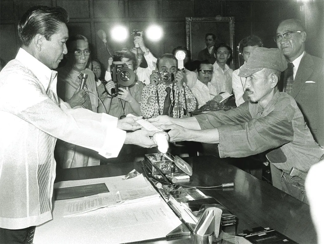 Japanese imperial army soldier Hiroo Onoda (R) offering his military sword to Philippine President Ferdinand E. Marcos (L) on the day of his surrender, March 11, 1974.