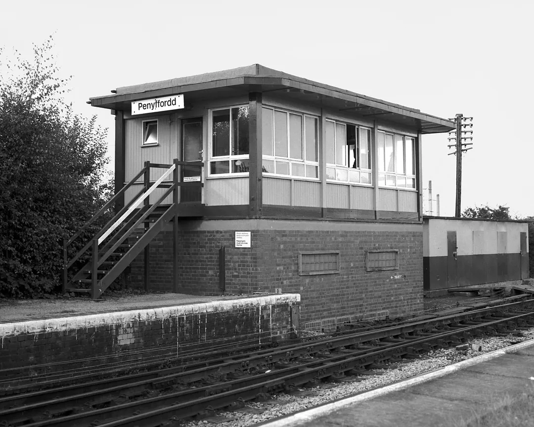 Penyffordd signal box located by the Down Main line at the north end of Penyffordd station. Monday 7th September 1987
Penyffordd signal box is a British Railways London Midland Region Type 15 design which opened fitted with a 25 lever London Midland Region Standard frame on 17th December 1972, replacing an earlier signal located just to the north. It was built using parts moved from Madeley Chord signal box which closed on 22nd August 1971

The signal box carries a pair of British Rail corporate identity printed design nameplates