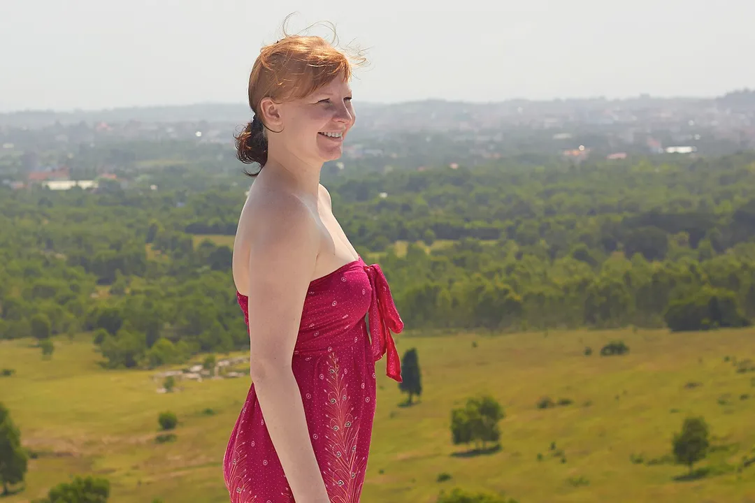Cambodia, Sihanoukville. Young woman in red dress on the hill against the background of the city Sihanoukville.