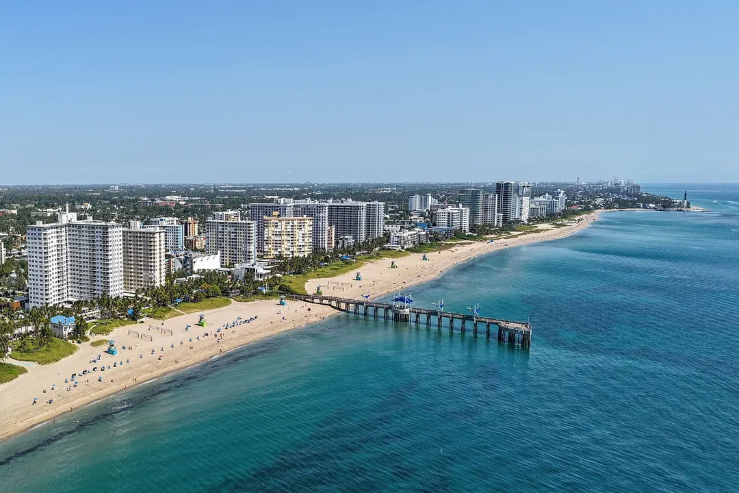 Aerial view of Pompano Beach, Florida, a coastal city of 112,046 residents, showing the beachfront, Fisher Family Pier and Hillsboro Inlet Lighthouse.