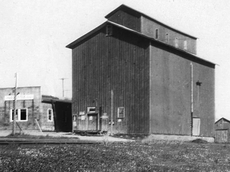 The Port Perry mill and grain elevator, circa 1930. The building remains a major landmark to this day. A line of the Port Whitby and Port Perry Railway runs across the foreground, although it is not clear in this image if this was the spur that ended at the elevator, or the mainline passing to Lindsay. The elevator was built in 1873 by George Currie and was later sold to Aaron Ross. The building was referred to as the Ross Elevator for years. By the time of this image, it was owned by Hogg &amp; Lytle, with their offices located in the smaller building on the left. Today it used by an auto parts distributer, and the two buildings have been connected, with additional storage built on the right.