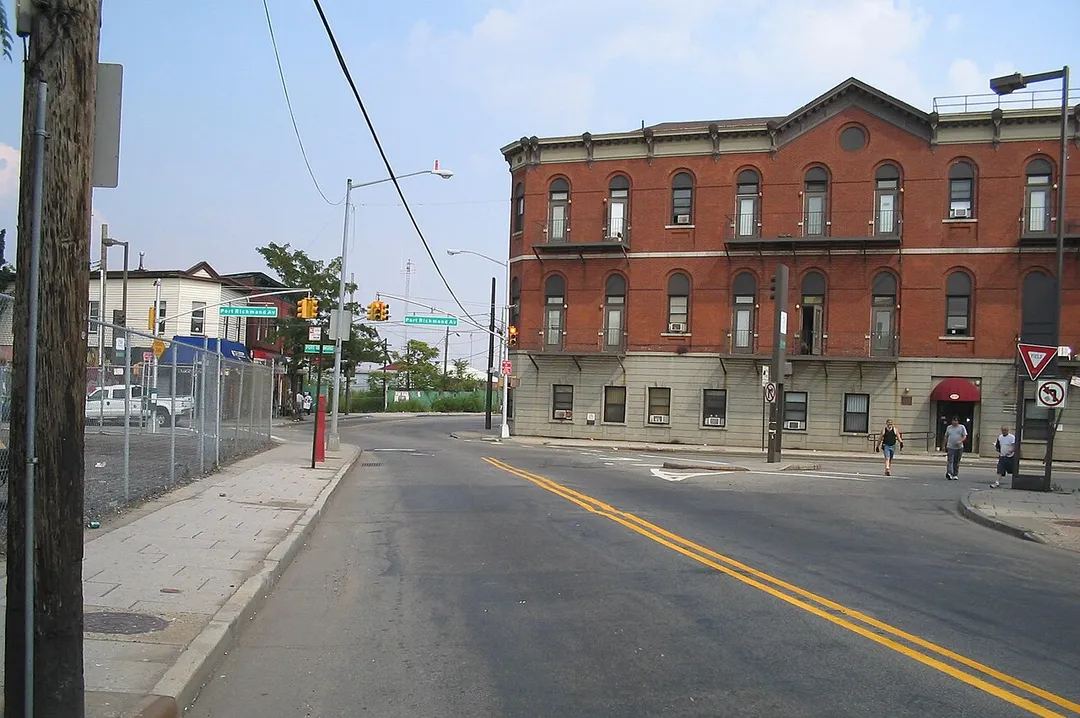 Looking east from Richmond Terrace and Ferry Street, at the corner of Richmond Terrace and Port Richmond Avenue, known in the past as Port Richmond Square. The red brick building in the photo replaced the hotel where Aaron Burr, 3rd Vice President of the United States, died. This was once a bustling center for business. Old photos and postscards reveal the presence a trolley line  on Richmond Terrace (street going forward) as well as other buildings which have since been demolished, such as on the corner to the far left. The Bergen Point Ferry to Bayonne, NJ, discontinued after the Bayonne Bridge opened, used to be in the distance (on the left of Richmond Terrace).
I took this photo in August 2005 with my own camera.
