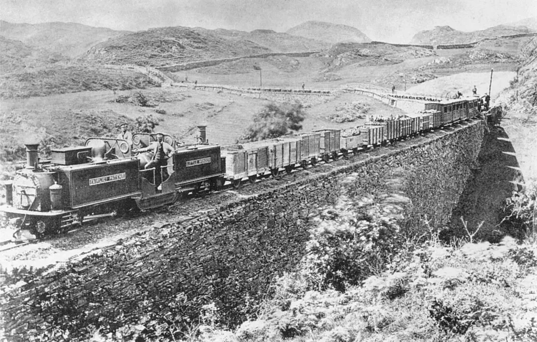 Festiniog Railway's first double Fairlie locomotive "Little Wonder" with long mixed train - consisting of loaded goods wagons, passenger carriages, and empty slate wagons - rounds Cei Mawr.