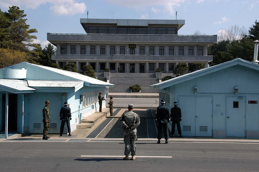 A view from South Korea towards North Korea in the Joint Security Area at Panmunjom.  North and South Korean military personnel, as well as a single US soldier, are shown.