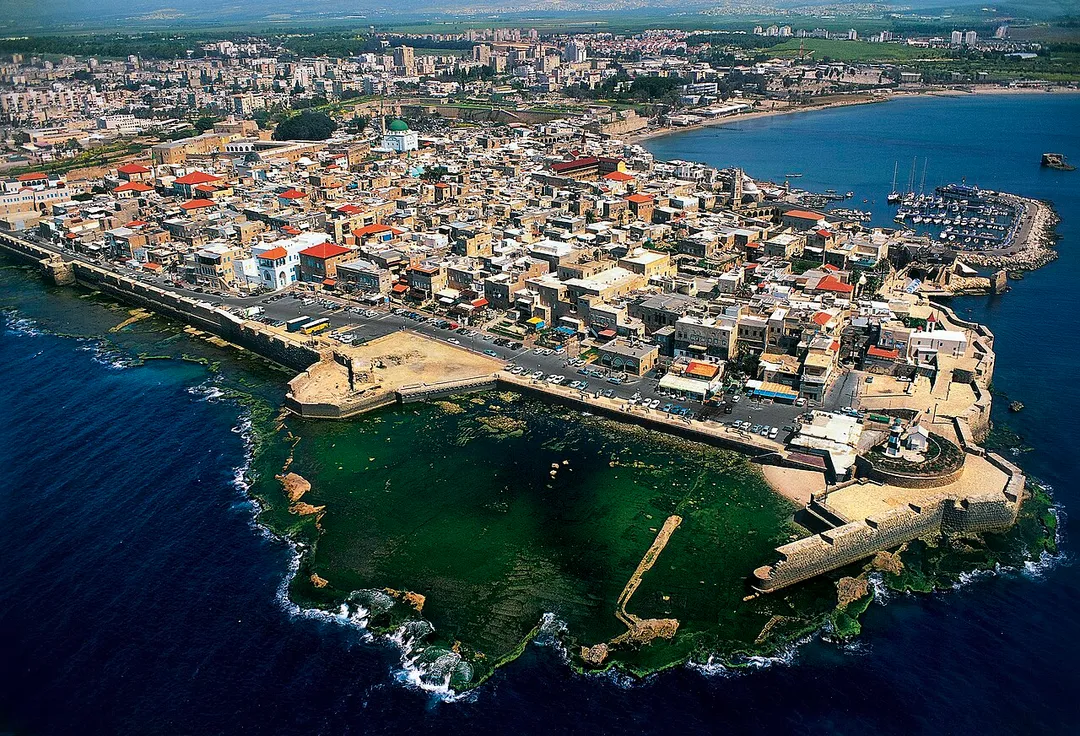Acre ( Acco) is a city in the Western Galilee region of northern Israel at the northern extremity of Haifa Bay. Acre is one of the oldest continuously inhabited sites in the country.Historically, it was a strategic coastal link to the Levant. Acre is the holiest city of the Bahá'í Faith. The picture shows an aerial view of the Old City, its harbour, the ancient walls and the Al-Jazzir Mosque. Photo by Itamar Grinberg.