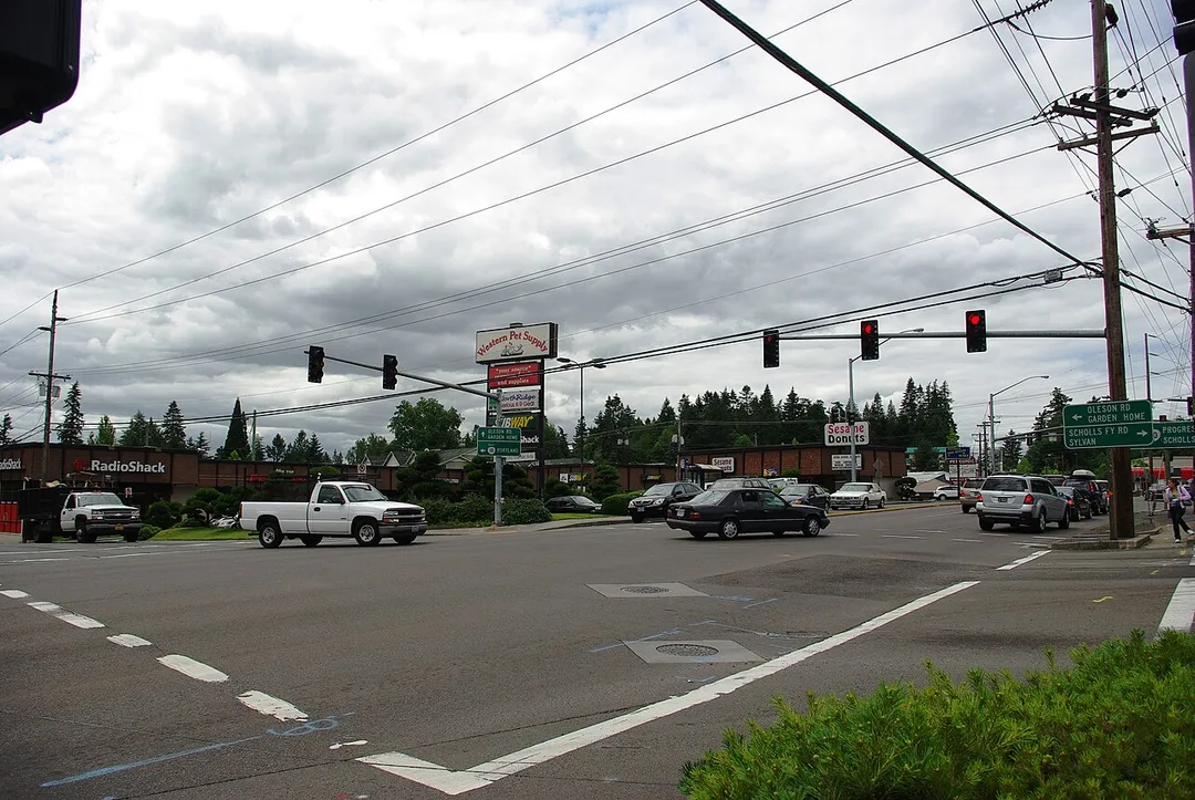 w:Raleigh Hills, Oregon, neighborhood near w:Portland, Oregon. w:Oregon Route 10 (Beaverton-Hillsdale Highway) runs from top to bottom; w:Oregon Route 210 (Scholls Ferry Road) is only visible in the distance underneath the far right red light. Oleson Road is on the left and ends at Scholls Ferry Road off-frame.