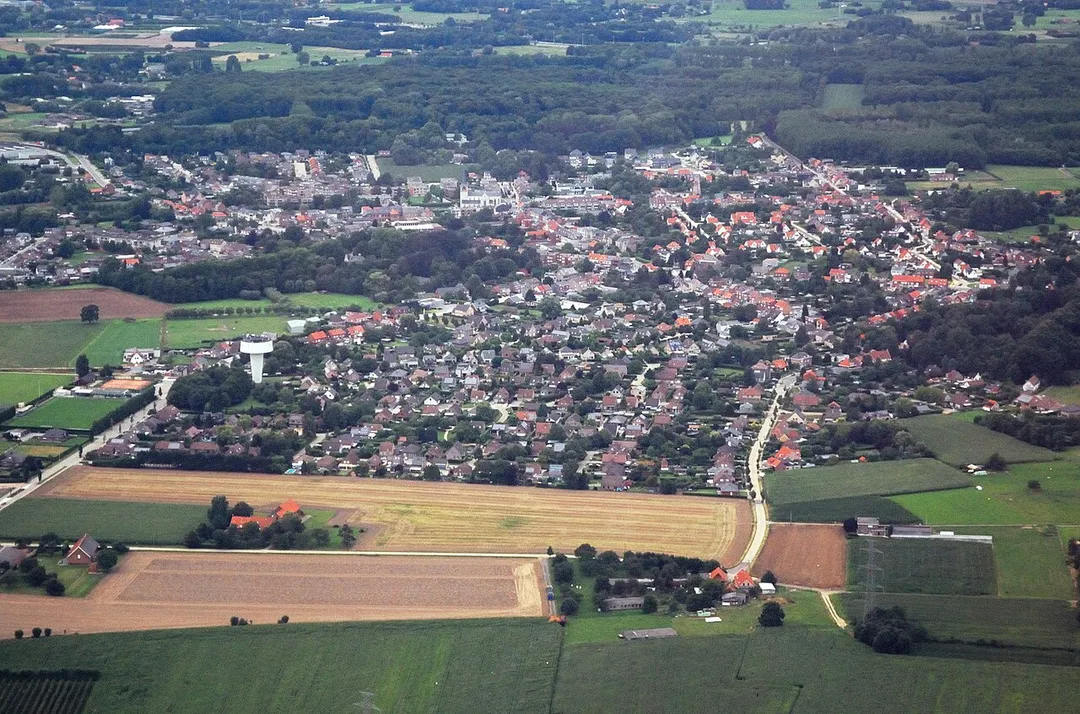 Aerial photograph of the village centre of Ranst, Belgium, viewed from the South. Nikon D60 f=55mm b/5.6 at 1/400s ISO 800. Contrast and colours enhanced using Nikon NX Studio 1.3.2. Straightened and framed using GIMP 2.10.34.