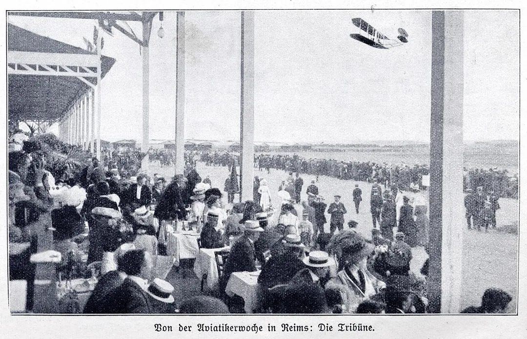 Photograph (taken from a catholic german magazin from 1910) of a biplane flying past the tribune of the Aviation week in Reims, France, August 22 - 29, 1909.