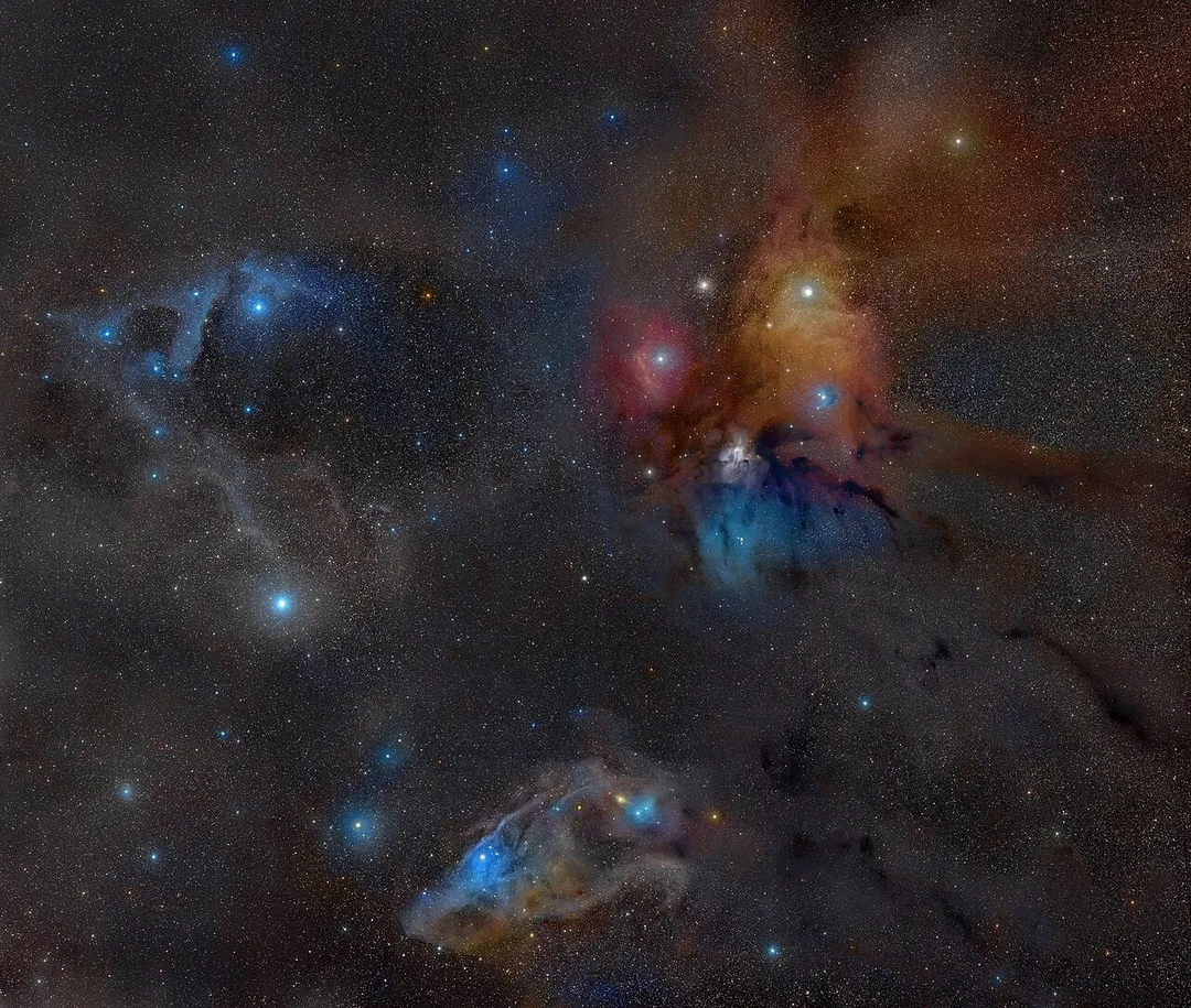 The binary star system Rho Ophiuchi. This star-forming region is located only 400 light years from Earth and is surrounded by a red emission nebula and numerous light and dark brown dust lanes. Nearby is the star Antares while the globular cluster, M4, is visible between Antares and the red emission nebula. Toward the bottom can be found IC 4592, the Blue Horsehead nebula. Note: the stars in this image appear large and white rather than in their true colors due to overexposure, and the image is much more luminous than in reality (with normal computer screen settings). Antares is the white dot in the yellow area. North is towards the bottom. M4 is to the left of Antares, and Sigma Scorpii is to the lower left of M4, in the red area. These three objects form three corners of a pentagon. The other two corners, proceeding counterclockwise, are HD 147889 (near IC 4603) and 22 Scorpii. Far to the left of the pentagon is Pi Scorpii and lower down Dschubba and Acrab, three prominent stars in the head and claws of the scorpion. The multiple star system Rho Ophiuchi itself appears as three white dots in the middle of the blue area just below the pentagon.