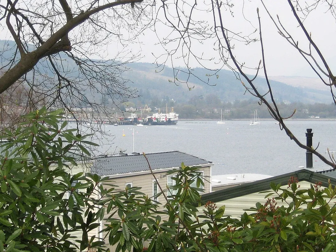 Rosneath caravan park, looking over the Gare Loch towards the former naval base, with MV Juno laid up at the pier, and MV Saturn alongside.