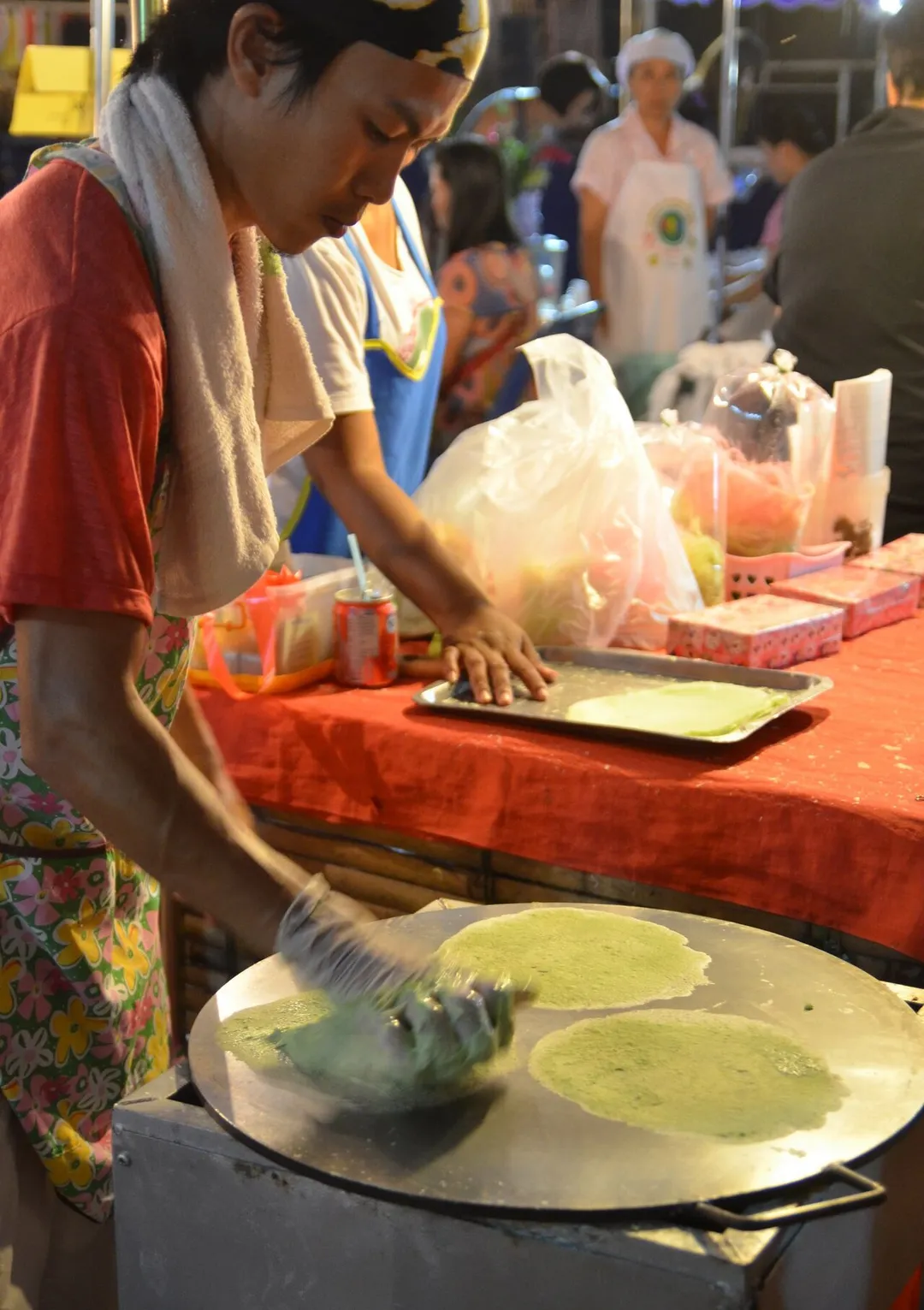 Making roti sai mai (Thai script: โรตีสายไหม). It literally means "silk roti" (roti is a flat bread of Indian origin). These ultra thin pancakes are made by rubbing a sticky dough on to a hot plate. They are used as a wrap for a kind of candy floss. This photo was made at a night market in Uttaradit, Thailand. The final result can be seen here.