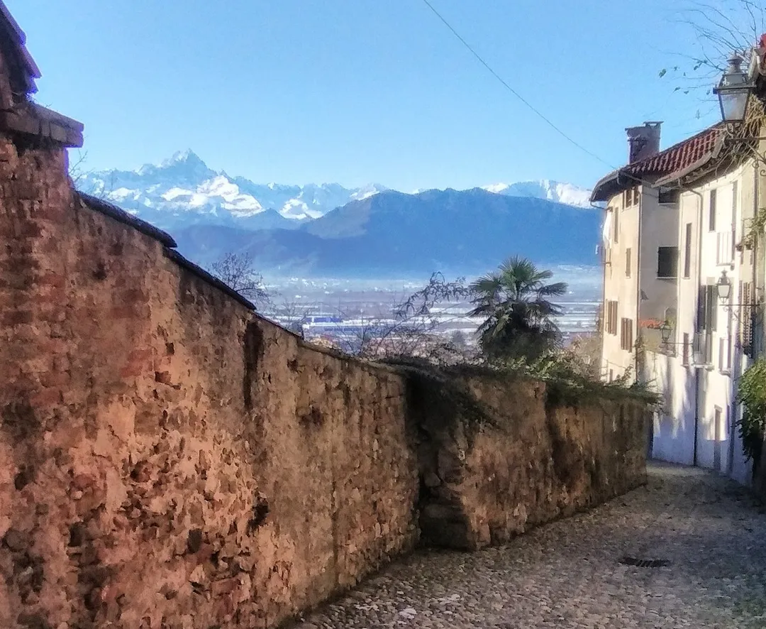 Street in medieval Saluzzo with the old city walls and Monviso in the distance