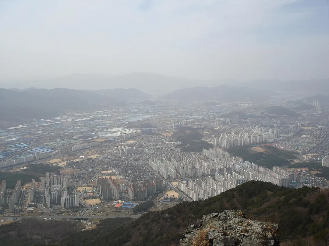 View of Changwon, South Korea. The Changwon Main Street (창원대로) can be seen dividing the city between the residential area in the north (on the right) and the industrial area in the south (on the left).The picture was taken from Mount Daeam (대암산).