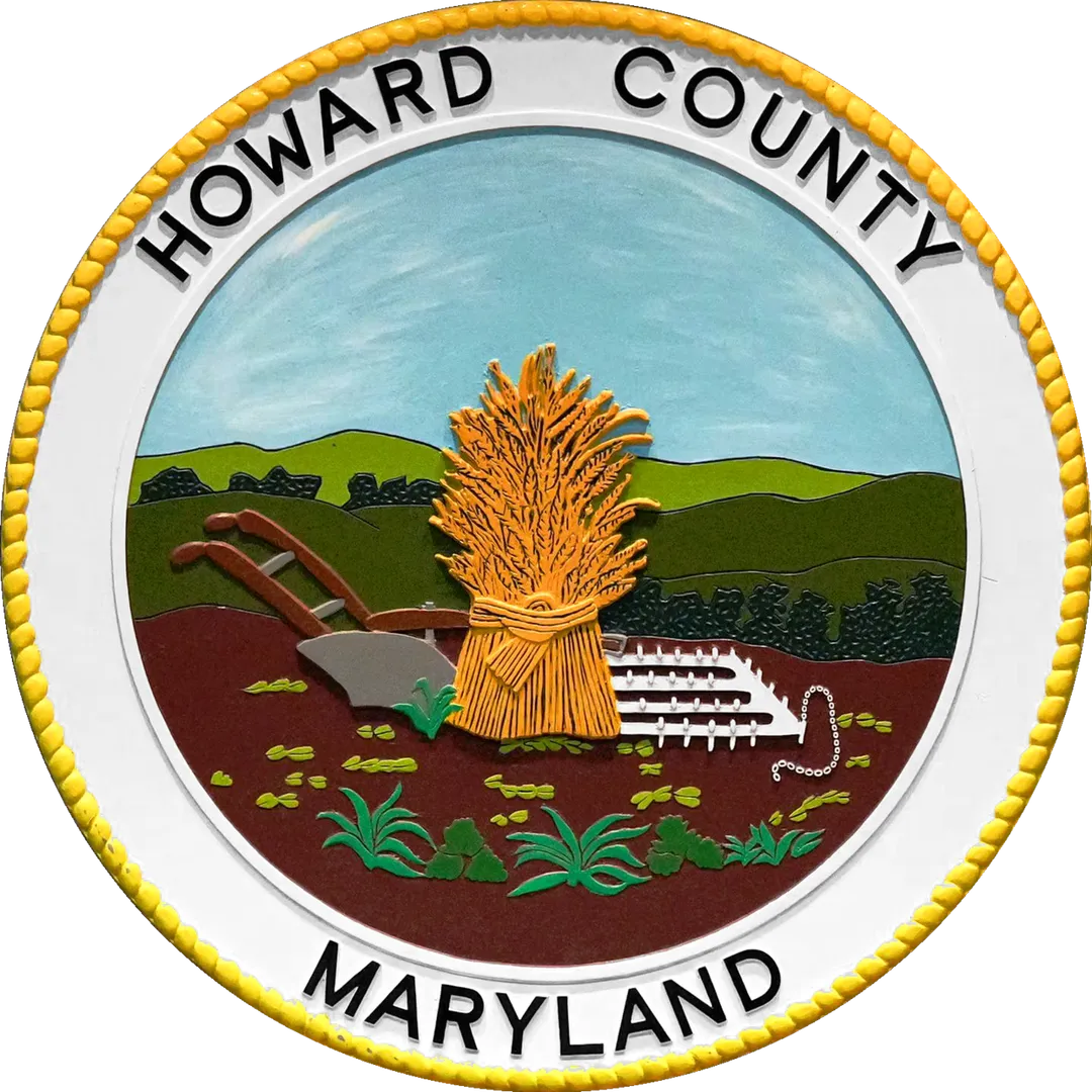 The seal of Howard County, Maryland. The Howard County Seal was designed and approved on behalf of the Howard District of Anne Arundel County in 1840, but the County was not officially established until Howard District was separated from Anne Arundel County in 1851. The seal was designed by Edward Stabler, one of the foremost seal designers of the time (He also designed seals for Anne Arundel County). 
The Howard County Code of 1977 stipulates that the seal of the county shall be a copy of the seal designed by Edward Stabler in 1840. The seal depicts "a shock of wheat, centrally dominant, with a hand plow to the left, and a spike harrow to the right. All three (3) are centered on a plowed field with tobacco plants growing in the foreground. Trees and rolling hills form the background, and a cloudless sky forms the upper third of the design." 

The County Code describes the colors that are to be used when the seal is rendered in color. The sky--Prussian blue-med.; the wheat--yellow ochre; the hills--graduated shades of teraverte; the tobacco plant in the foreground--Chrome green-med.; the trees--a dark shade of chrome green; the soil--burnt umber-med;.; the spike harrow and the plow blade--Ivory black diluted to gray; and the plow handles--Burnt sienna-med.