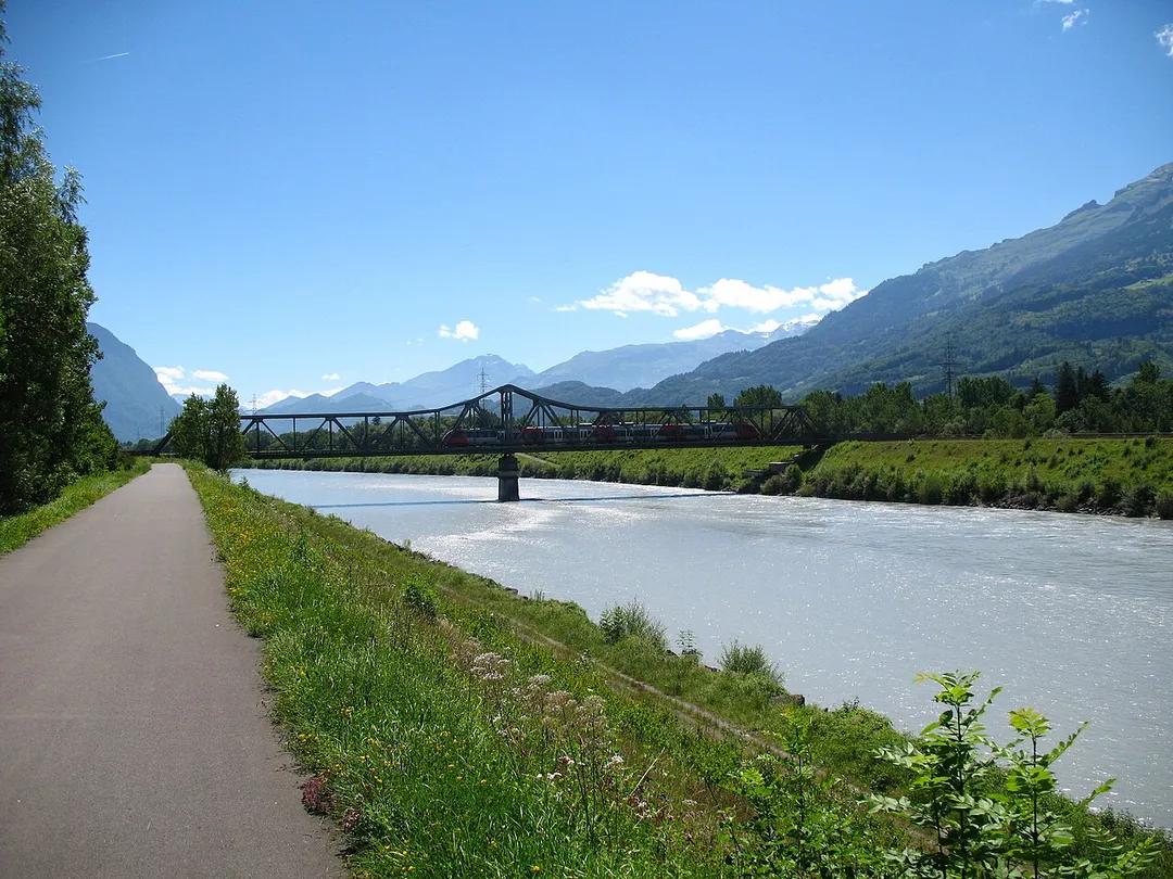 An Austrian EMU 4024 (Bombardier Talent) of the ÖBB is crossing the Rhine and the border of Liechtenstein and Switzerland, seen from the Rhine Causeway at Schaan-Vaduz