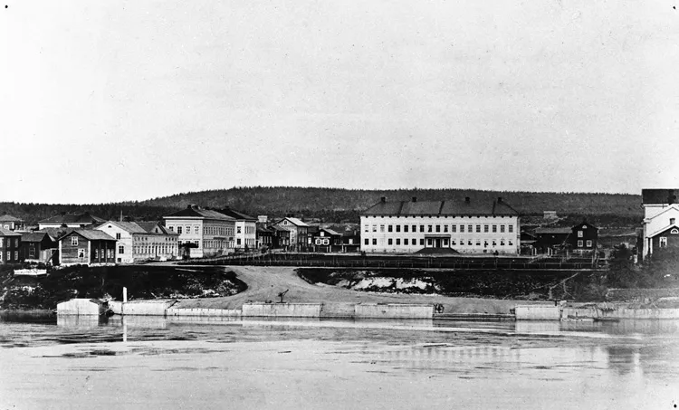 Skellefteå 1870. Bildbeskrivning: "Förnämlig arkitektur och mera anspråkslös bebyggelse kring torget och kajen 1870".