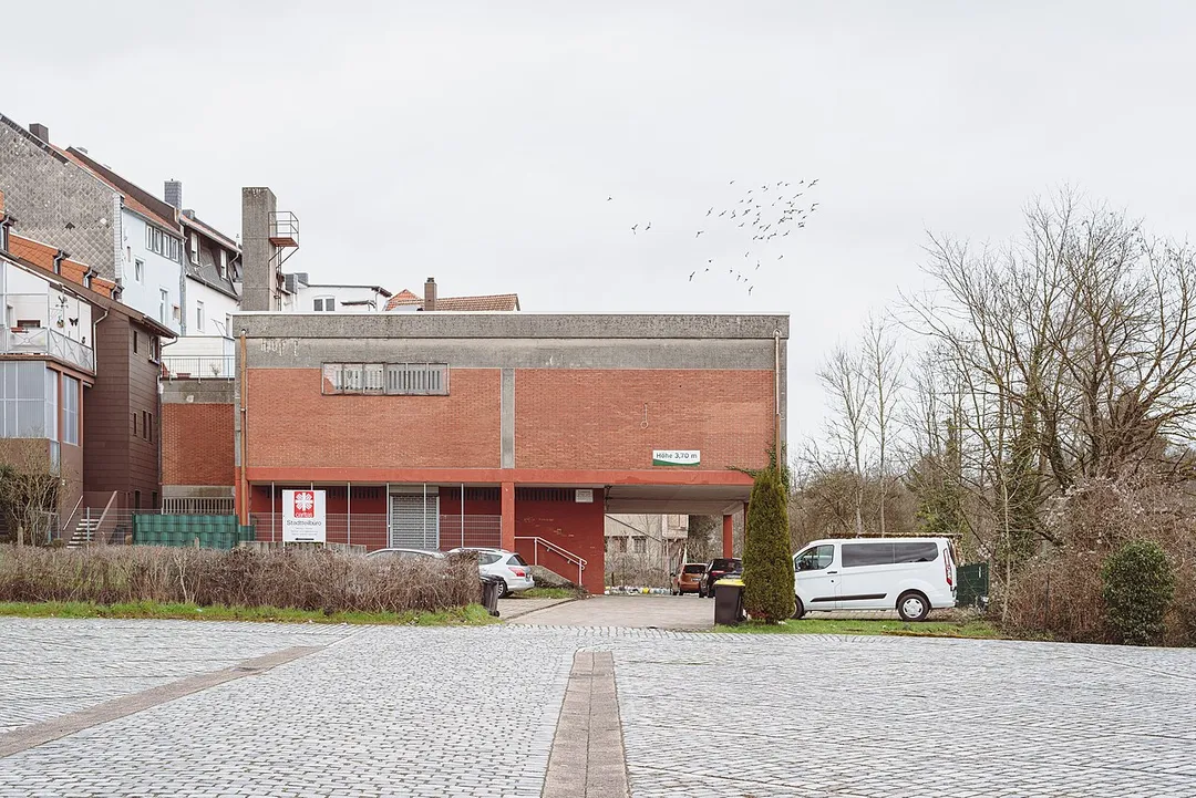 The rear building at the Sulzbachtalstraße 42 in Sulzbach/Saar. Above it flies a group of pigeons.