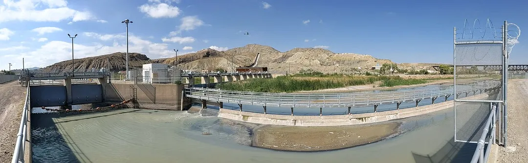 American Dam and Canal pano, El Paso, Texas, with mountains of Mexico (left) and New Mexico (right) in the background.  The dam and diversion weirs are in the center; canal at left; railroad bridges over the Rio Grande upstream at right; cross on Mount Cristo Rey in center background.