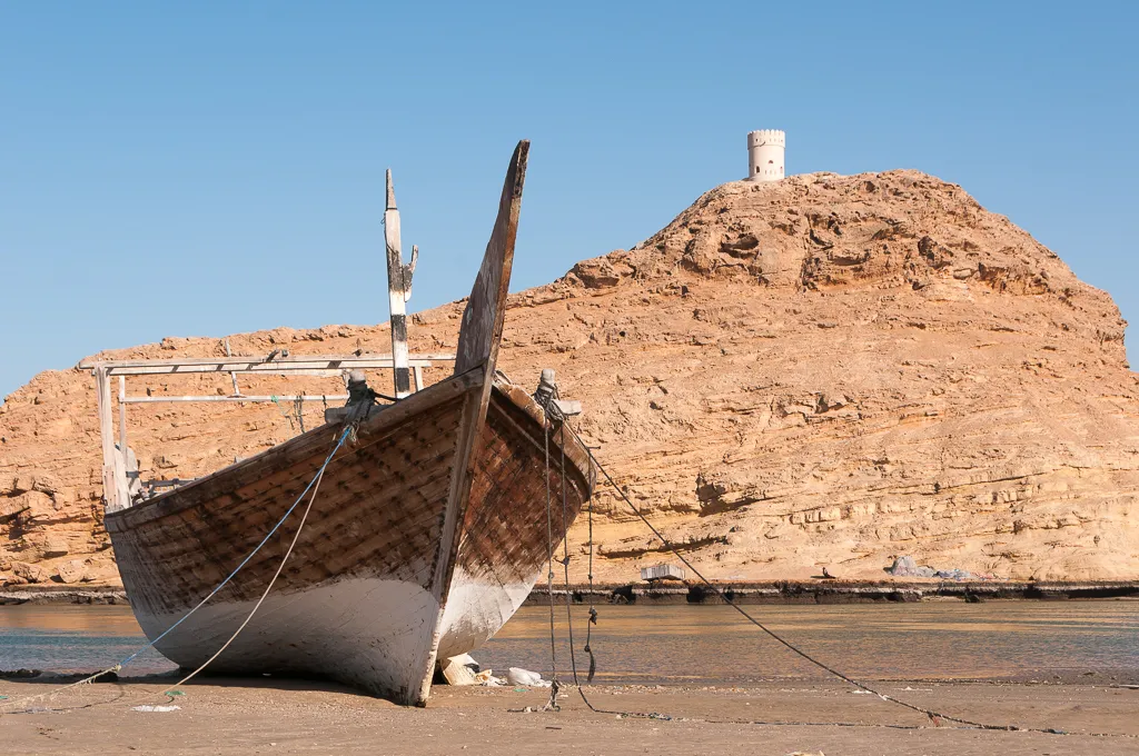 Dhow with Al Ayjah watchtower in Sur, Oman.