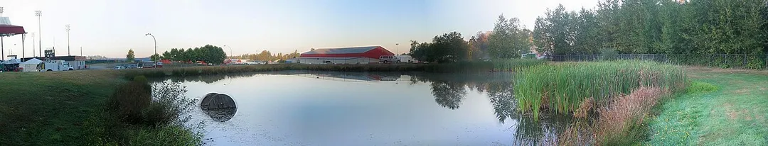 A panorama of the Cloverdale Fairgrounds To the left is the Stetson Bowl Stadium; the Show Barn (white) and the Agriplex (red) are at center, reflected by the pond. Photo taken at sunrise. Surrey, BC, Canada.