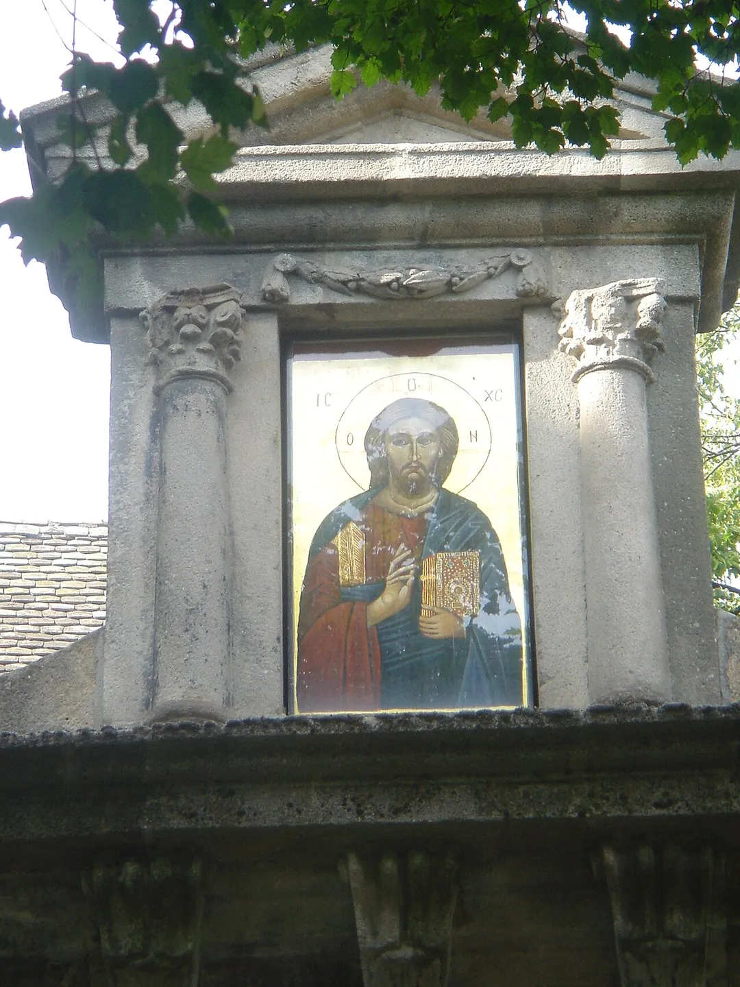 A sunlit icon of Jesus above the gate to a Serbian Orthodox church in Szentendre.