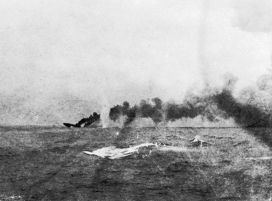 In the distance the British battlecruiser HMS Indefatigable sinking after being struck by shells from the German battlecruiser Von Der Tann first in "X" magazine and then once she had limped out of the line she was hit by another salvo on the foredeck, the resulting explosion then destroying her. All but two of Indefatigable's crew of 1,119 were killed in the blast.