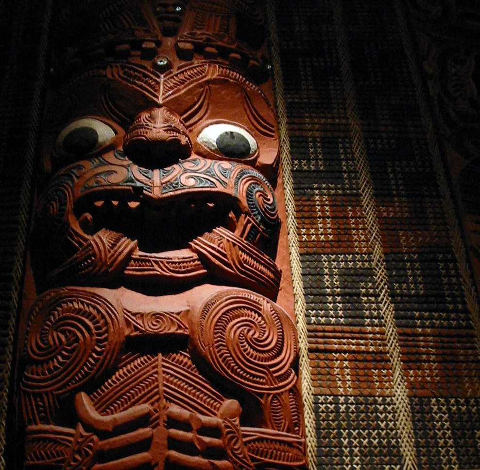 Detail of carved post from the Māori meeting house Hotunui, Ngāti Maru, Hauraki, 19th Century. Tukutuku wall panels visible to right of post. Hotunui was built in 1878 and now stands in the Auckland War Memorial Museum, New Zealand.