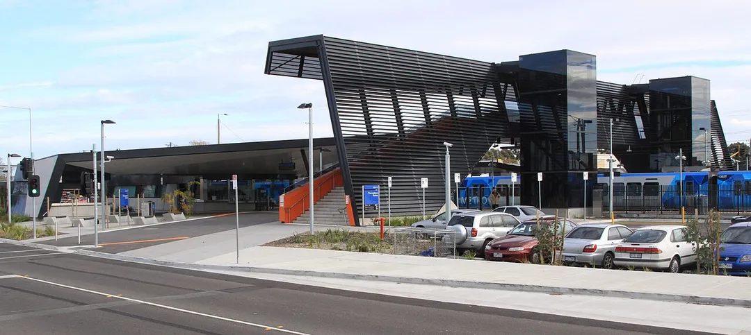 Eastern side of w:Thomastown railway station, Melbourne showing the station building on platform 1 and the pedestrian overpass. A Metro Trains liveried XTrapolis train is in platform 2.