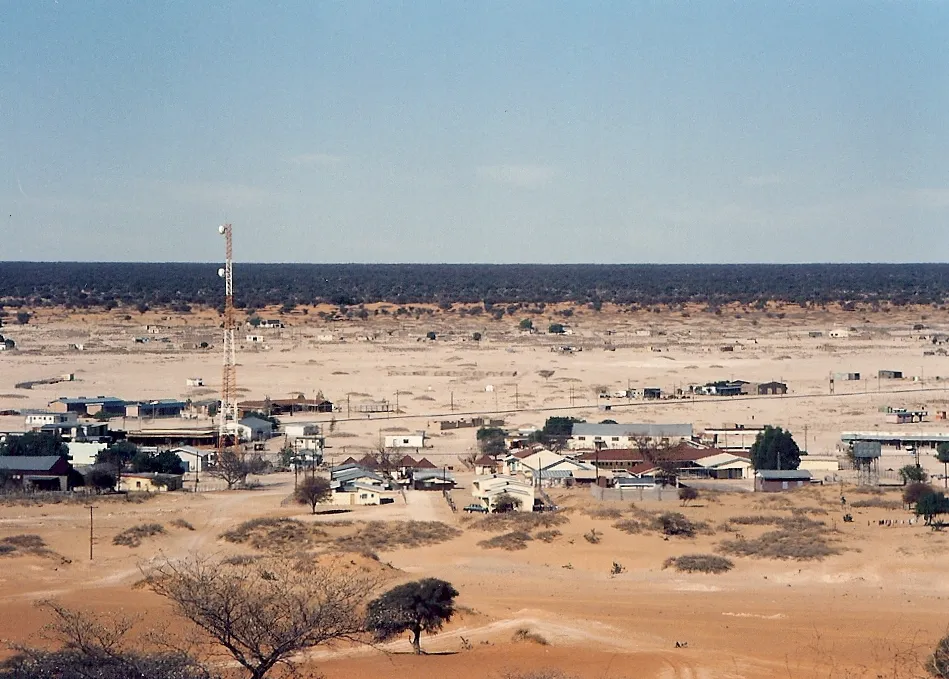 The town of Tshabong, the administrative centre of Kgalagadi District, in the Kalahari Desert, Botswana. Although this is mid-winter – the dry season – there is still a fair amount of foliage outside the town, beyond the immediate grazing range of goats and camels. The mast is probably a microwave transmitter, linked to Botswana Telecom's landline network (no mobile phones in Botswana in 1995!). Taken in mid-1995 on film.