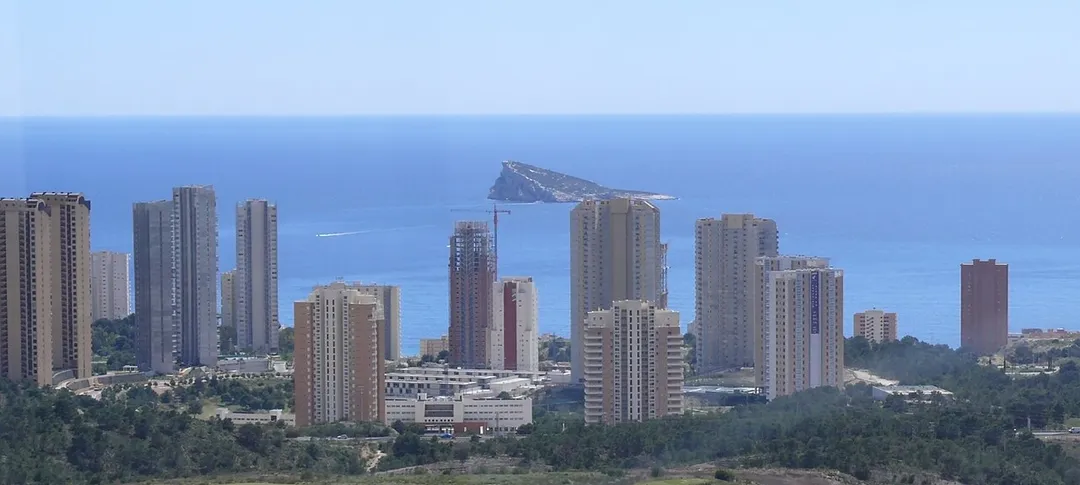 The skyline of Benidorm. Benidorm is a Valencian coastal town and municipality located in the province of Alicante, Spain, by the Mediterranean Sea. It is a very popular seaside resort.