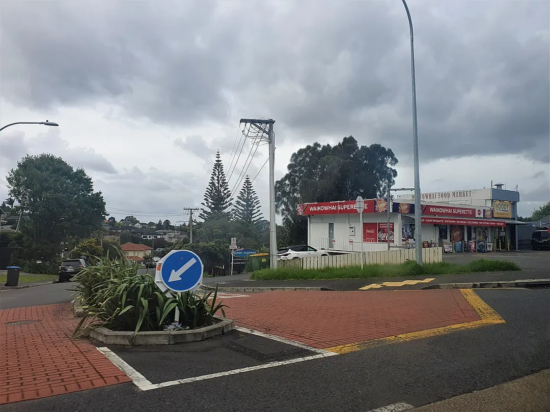 A view of Waikowhai, a central Auckland suburb in New Zealand, showing Waikowhai Superette and Noody Thai restaurant at the corner of Hillsborough Road and Quona Avenue.