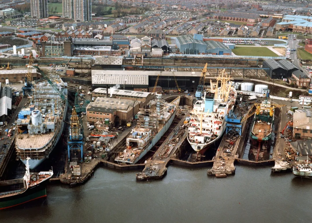 Swan Hunters dry docks, Wallsend 26th March 1987.
From left to right the docks hold a Royal Fleet Auxiliary tanker, a Royal Navy warship, a Nigerian registered cargo vessel and an off shore supply vessel.
Reference Number: TWAS: DS.SWH.5.3.1.12.6
(Copyright) We're happy for you to share this digital image within the spirit of The Commons. Please cite 'Tyne &amp; Wear Archives &amp; Museums' when reusing. Certain restrictions on high quality reproductions and commercial use of the original physical version apply though; if you're unsure please email archives@twmuseums.org.uk.

To purchase a hi-res copy please email archives@twmuseums.org.uk quoting the title and reference number.