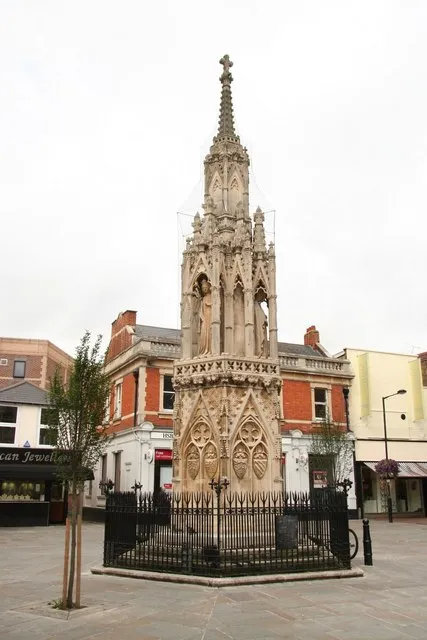 Waltham Cross One of the three remaining of the original 12 Eleanor crosses erected by King Edward I to mark the overnight resting places of the funeral cortege of Queen Eleanor, following her death in Harby on November 28th 1290.
Architecturally, it follows the same design as the cross at Northampton https://www.geograph.org.uk/photo/535329 and the lost crosses of Cheapside and Charing in London, though more Decorated in style. Hexagonal in plan, it rises through diminishing stages of blind tracery with heraldic motifs, through a second tier of six elaborate pinnacled canopies. These house three statues of Eleanor in traditional pose by master mason Alexander of Abingdon, to a third hexagonal tier of blind tracery surmounted by a cross. 

Waltham Cross has somehow miraculously survived more than 700 years of adversity including Civil War, encroachment by adjacent buildings, road schemes for turnpikes, the misguided intentions of Victorian restorations and bombs dropped during the Second World War. It now stands much restored and rather ignominiously as the centrepiece of a modern pedestrian shopping area.