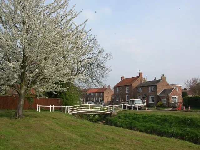 Village green and beck, Wilberfoss, East Riding of Yorkshire, England.One of the bridges over the beck is viewed from a bench on the village green.