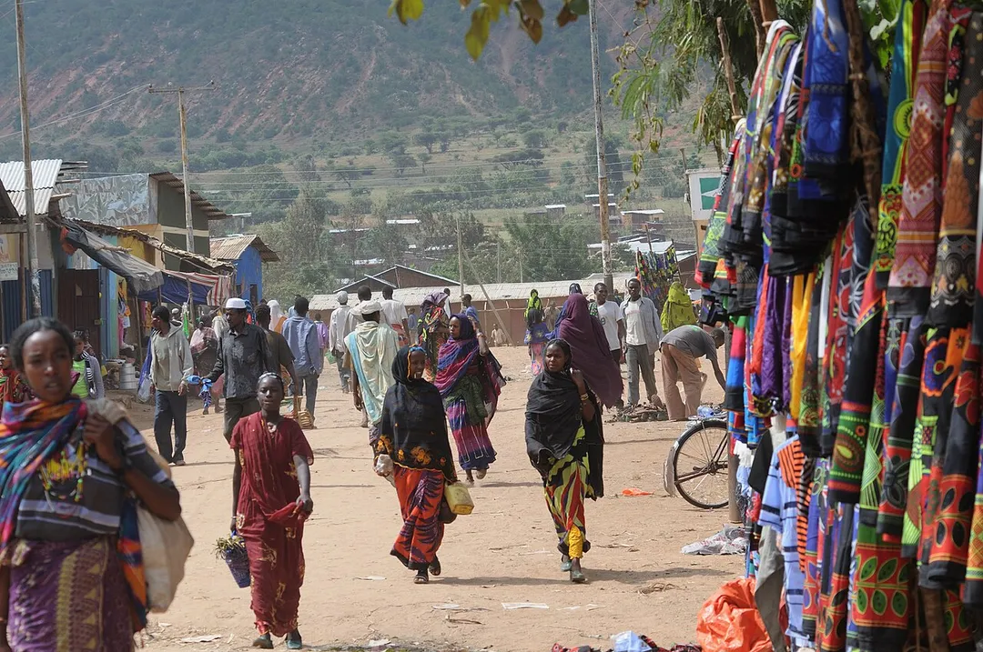 Market street in Yabelo with pedestrians, vendors and stalls selling clothing and other goods.