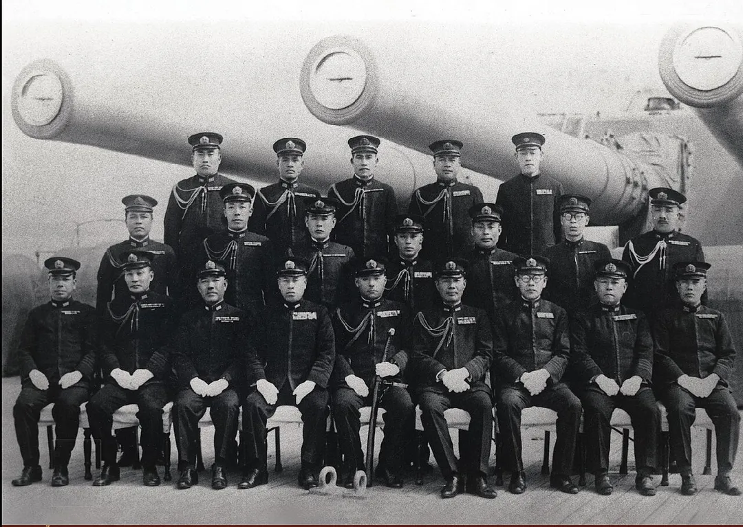 Admiral Yamamoto and his staff posing with the battleship Yamato's 18.1-inch (46 cm) gun turret 3 shortly after commisioning