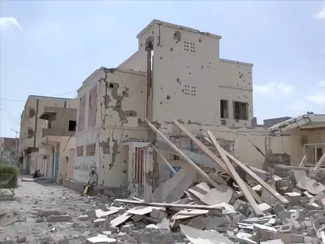 A man sitting by a destroyed building in Zinjibar